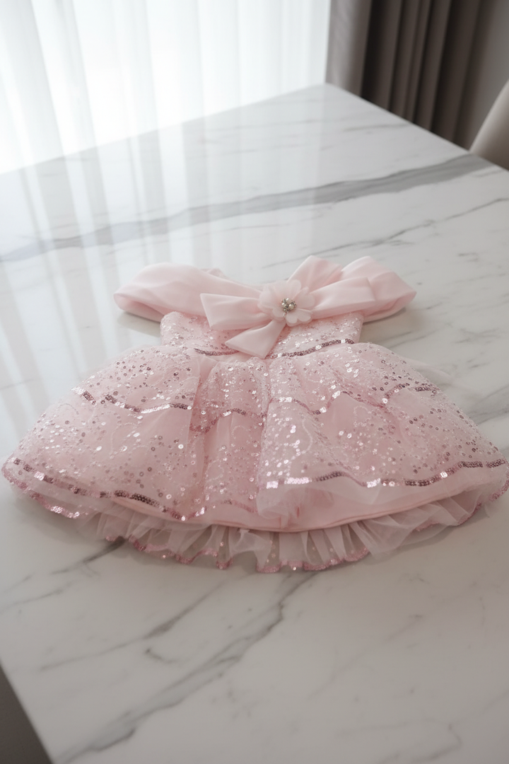 Robe rose sequins posée sur une table en marbre blanc
