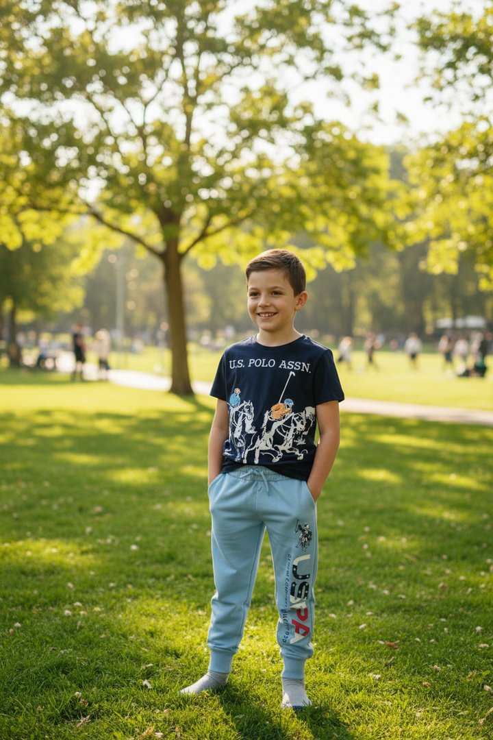Garçon souriant en ensemble U.S. Polo Assn. marine et bleu ciel, ambiance lifestyle extérieure