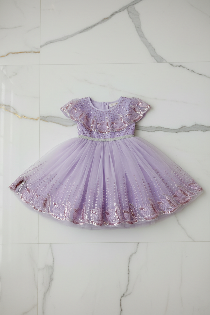 Robe violette à paillettes étalée sur surface marbre moderne et chic