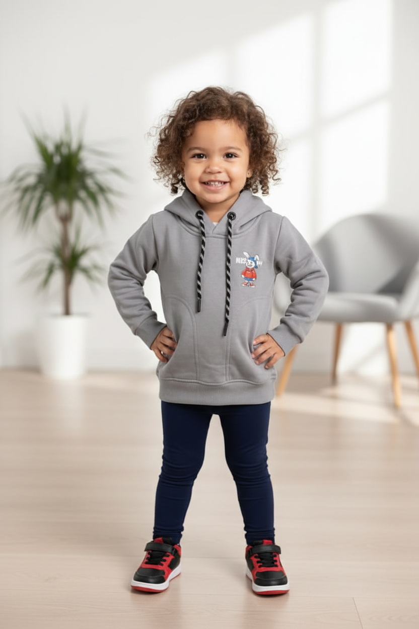 Petite fille afro portant le hoodie gris unisexe CHAYA STYLE, pose debout, intérieur moderne